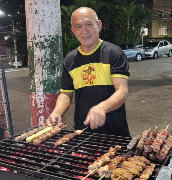 Aluno virando espetinhos na brasa à noite